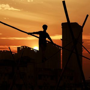 Silhouette of a man performing a balance exercise at sunrise.
